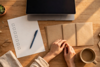 Overhead view of a desk with a laptop, bill checklist, envelopes and coffee — planning to switch banks without missing bills